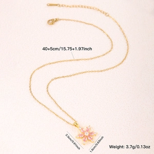 Elegant gold necklace with pink flower pendant and zircon accents on beige background