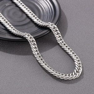 Polished silver stainless steel cuban curb chain necklace on a dark textured background