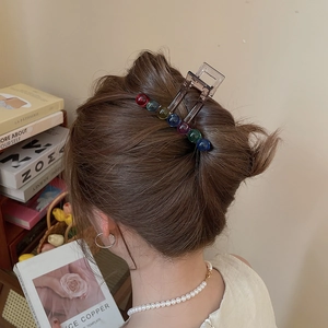 Brown acrylic hair claw clip with colorful beads shown on a woman's bun hairstyle