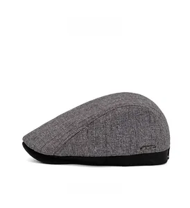 Detail view of charcoal gray newsboy cap featuring side metal brand plate and textured fabric