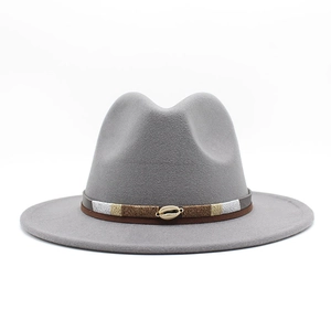 Detail of grey wool fedora hat featuring a bohemian woven band and golden cowrie shell