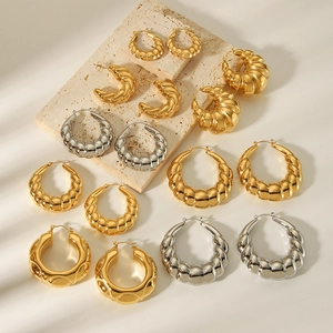 18K gold and silver hollow twisted hoop earrings set displayed on beige stone