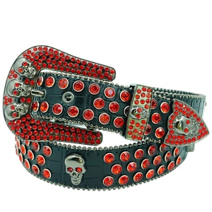 Close-up of black crocodile pattern belt with red rhinestones and metal skull details