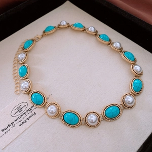 Macro shot of vintage gold necklace with turquoise stones and elegant pearls