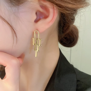 Detailed view of long geometric gold linear drop earrings styled on a model's ear