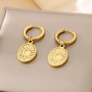 Close-up of gold oval sun and moon earrings with textured edges on a jewelry box