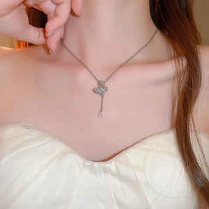 Close-up of elegant silver butterfly necklace with tassel and drop pendant on neck