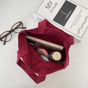 Top view of spacious burgundy canvas tote bag interior showing daily essentials and snap button