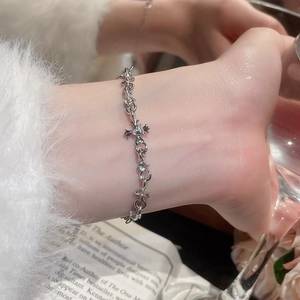 Silver bracelet featuring hollow cross charms with a sparkling zircon on a woman's wrist