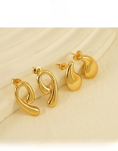 Detailed view of gold plated teardrop earrings and twisted stud on a display stand