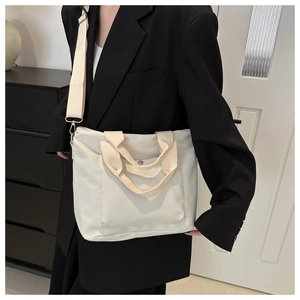 Detalle del bolso tote de nailon blanco crema con bolsillo frontal y correa ancha