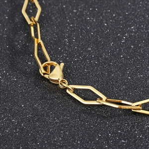 Macro detail of gold geometric hexagonal chain links and lobster clasp on a steel necklace