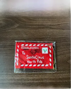 Detailed view of a red felt Christmas envelope ornament with gold string on wood