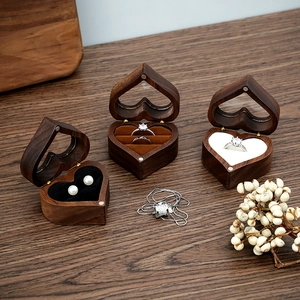 Handcrafted heart-shaped walnut wood ring box with velvet lining on dark wood tabletop