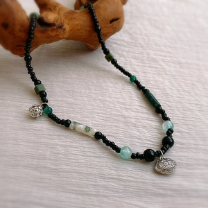Détail du collier ras du cou perlé avec pendentifs Ruyi et lotus sur bois naturel