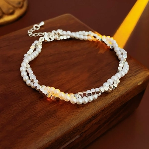 Detail of double-layer bracelet with white pearls and silver hexagonal metal beads on wood