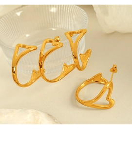 Detailed close-up of three elegant gold heart-shaped hoop earrings on a light surface