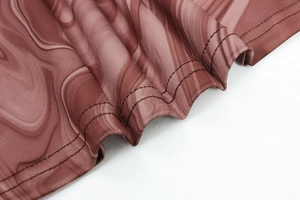Détail de couture double aiguille sur l'ourlet d'une robe stretch à motif marbré