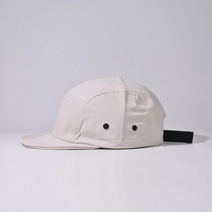 Detail of light beige 5-panel camper hat featuring black metal eyelets and adjustable strap