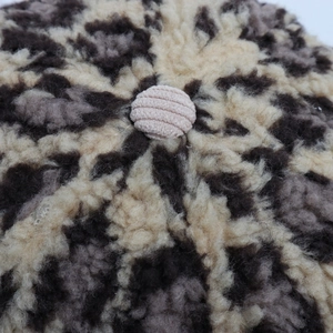 Detailed macro view of a leopard print fuzzy cap featuring a beige corduroy top button