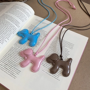 Vue détaillée de trois colliers avec pendentifs chiots colorés sur un livre ouvert