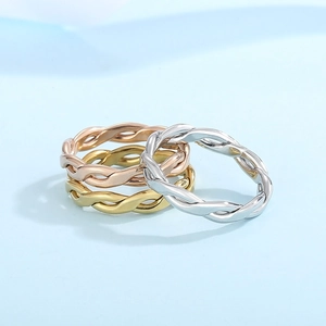 Macro detail of twisted rope rings in gold, silver, and rose gold stacked on blue base