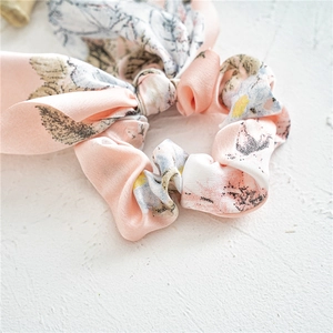 Elegant floral satin hair scrunchie with bow tie detail in soft pink and blue tones