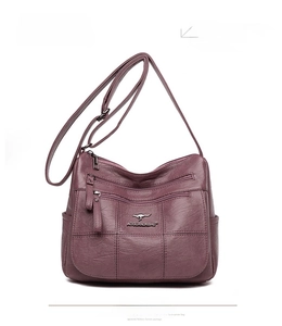 Detail of purple crossbody bag with pebbled texture and metal zipper accents