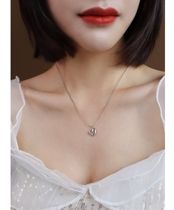 Close-up of heart pendant necklace in silver finish worn by a model with soft lighting