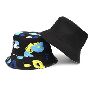 Dettaglio del cappello reversibile con lato nero minimalista e stampa graffiti astratta