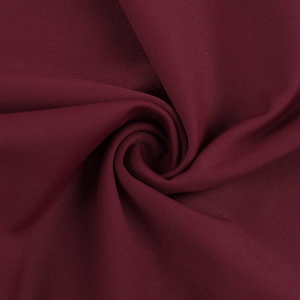 Detail of wine red dress fabric with elegant spiral pleated texture and smooth drape