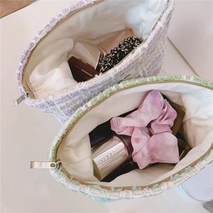 Detailed top view of tweed makeup bags showing interior storage and metal zipper