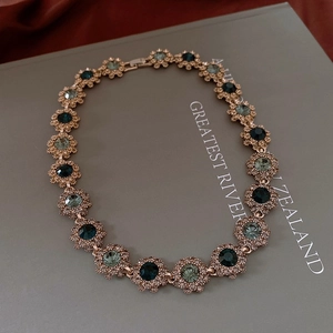 Macro detail of vintage floral necklace with emerald crystals and pavé diamond edges
