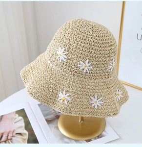 Close-up of beige straw sun hat with detailed 3D daisy flowers and textured weave