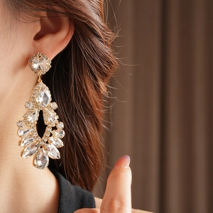 Close-up of gold hollow teardrop tassel earrings with sparkling rhinestones on model