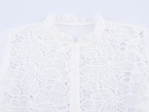 Close-up of white lace blouse featuring a ruffled stand collar and floral hollow details