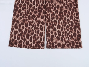 Detail view showing leopard print pattern and hem stitching on flowy trousers legs