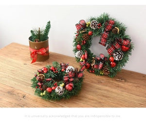 Detail of Christmas wreath with red plaid bow, pine cones and berries on wood table