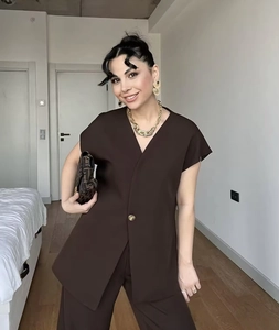 Detail of dark brown V-neck short-sleeve top and trousers set on a model in home setting