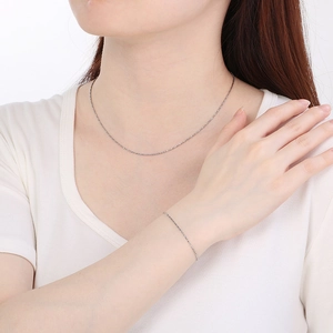 Close-up of a silver adjustable needle necklace and bracelet set on a model in white