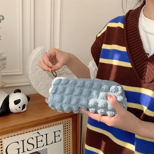 Close-up of light blue bubble texture fabric pouch held by a hand in a cozy room