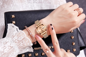 Luminous quartz watch with gold mesh band and matching jewelry set on a model wrist