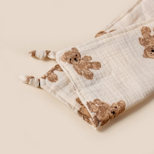 Détail d'un doudou en mousseline douce avec imprimé oursons et bords noués décoratifs