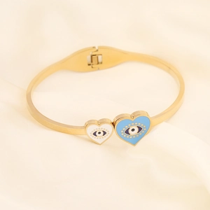 Golden evil eye heart cuff bracelet with blue and white enamel inlay on cream fabric