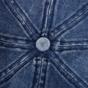 Macro view of blue denim crown with central button and contrast stitching detail