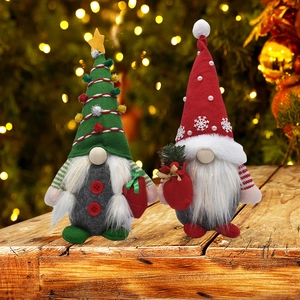 Détail de deux gnomes de Noël en peluche rouge et vert sur une table en bois avec effet bokeh