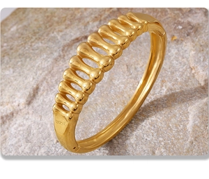 Detailed view of the gold fishbone hollow bangle on natural textured rock background