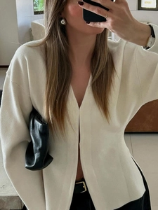 Close-up of white V-neck knitted cardigan showing long sleeve texture and soft fabric fit