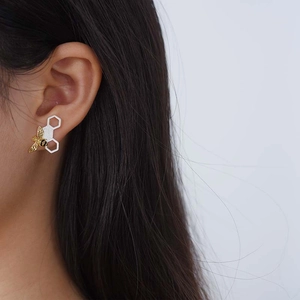 Detail view of a 925 sterling silver honey bee earring worn on a model's ear