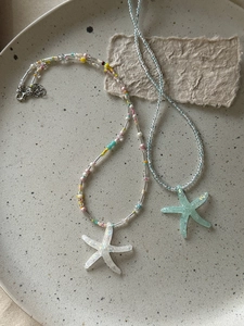 Detailed top view of colorful starfish beaded necklaces in a ceramic plate for summer